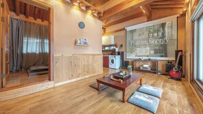 A cozy living room with wooden floors, a sofa, a coffee table, and a large window with a view of the outside. - Yangpyeong Vivaco Hanok Stay (Yangpyeong)