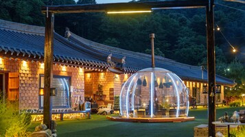 Un edificio tradicional con techo de tejas, una estructura de cúpula de vidrio transparente y un espacio exterior bien iluminado.