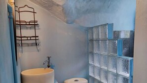 A compact bathroom with a sink, toilet, and a shelf unit against the wall. - Cozy 2-bedroom townhome in charming Provincia de Puntarenas with AC, WiFi (Provincia de Puntarenas)