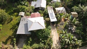 An aerial view of a residential area with multiple houses, each with a distinct roof structure and surrounded by lush greenery. - Cozy 2-bedroom townhome in charming Provincia de Puntarenas with AC, WiFi (Provincia de Puntarenas)