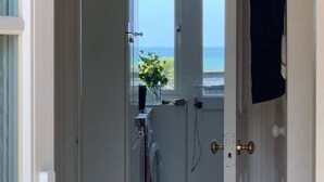 A doorway leading to a room with a view of the sea, a window with a view, and a door with a towel hanging on it.