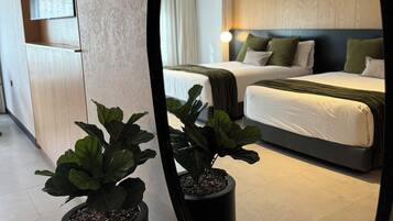 Una habitación de hotel moderna con una cama grande, mesitas de noche y un espejo que refleja el ambiente.