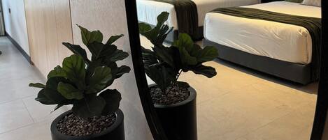 A modern hotel room with a large bed, bedside tables, and a mirror reflecting the room.