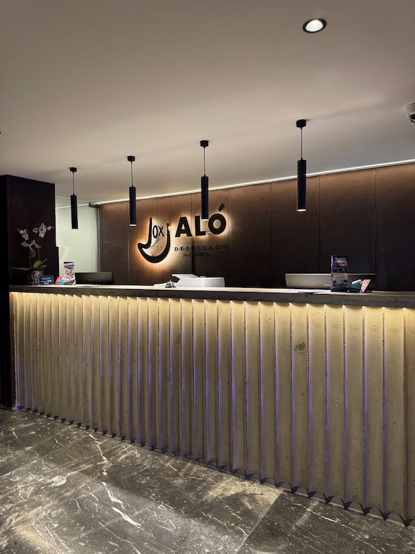 A reception desk with a modern design, featuring a logo and name 'Jox ALÓ' prominently displayed.