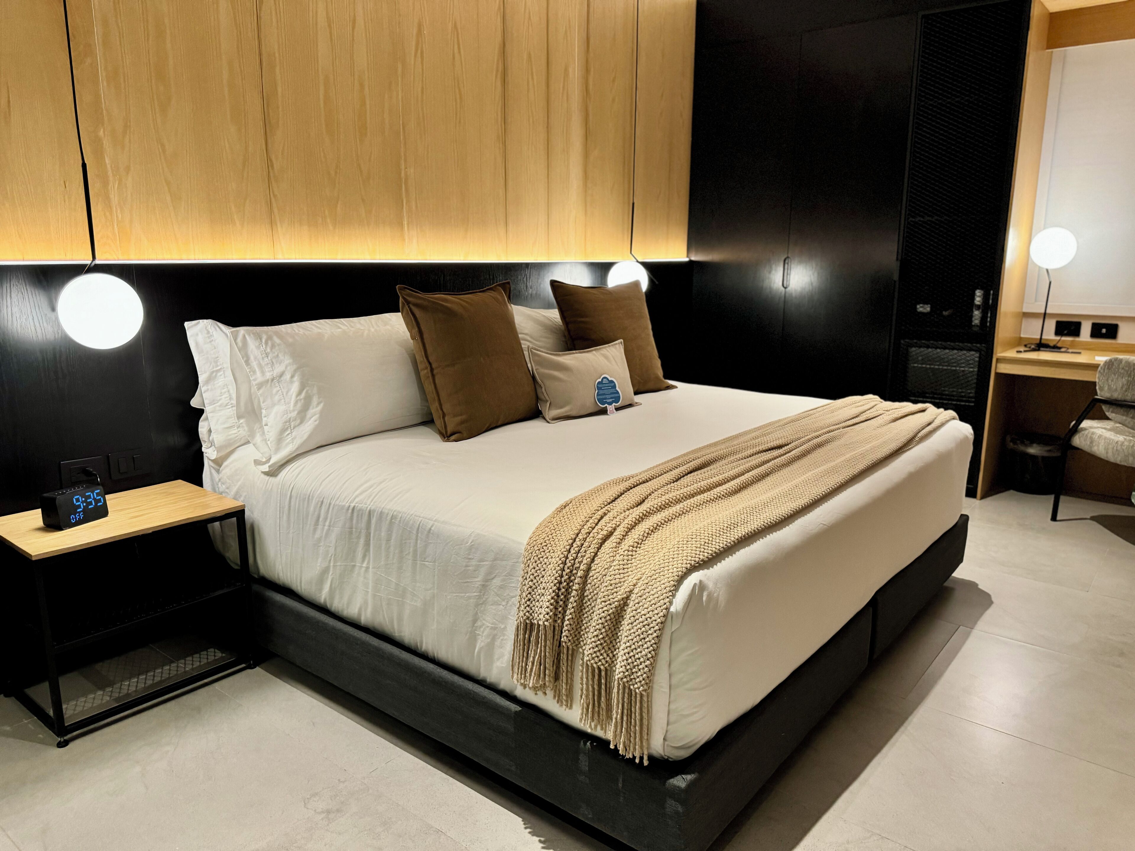 Un dormitorio moderno con una cama grande, mesitas de noche y un escritorio con una silla.