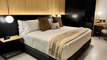 A modern bedroom with a large bed, bedside tables, and a desk with a chair.