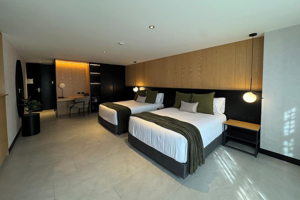 Une chambre d’hôtel moderne équipée de deux lits, d’un bureau et d’un coin salon.