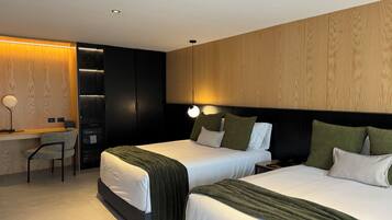 Quarto de hotel moderno com duas camas, uma escrivaninha e uma cadeira.