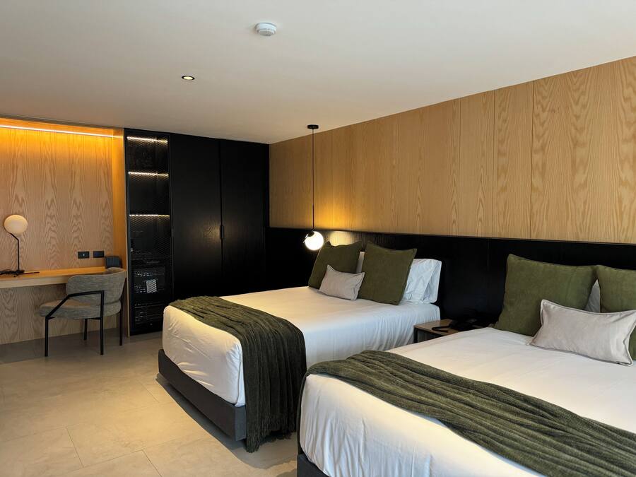 Quarto de hotel moderno com duas camas, uma escrivaninha e uma cadeira.