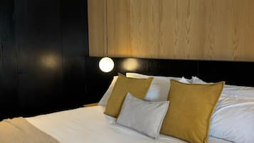 Quarto moderno com cama grande, cabeceira de madeira e luminária redonda na parede.