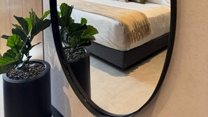 Moderni makuuhuone, jossa on suuri sänky, yöpöytä ja kaksi ruukkukasvia.