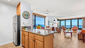 Eine moderne Küche mit einer großen Kochinsel, Holzschränken und Blick aufs Meer.