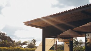 Un área de piscina al aire libre con sillones de descanso y una zona de estar cubierta.