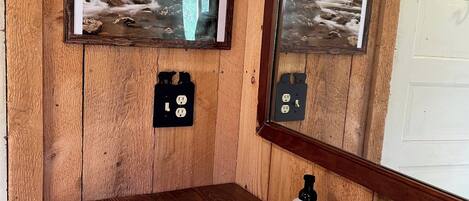 A wooden bathroom with a white sink, a mirror, and framed pictures of a forest.