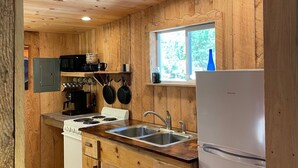 A wooden-paneled kitchen with a stove, sink, and refrigerator.