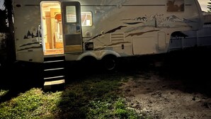 A recreational vehicle with an open door revealing a kitchen area, a small seating space, and a mural of a mountain scene. - Cozy mobile home  (Miami Gardens)