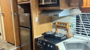 A compact kitchenette with a built-in microwave, refrigerator, and stove. - Cozy mobile home  (Miami Gardens)