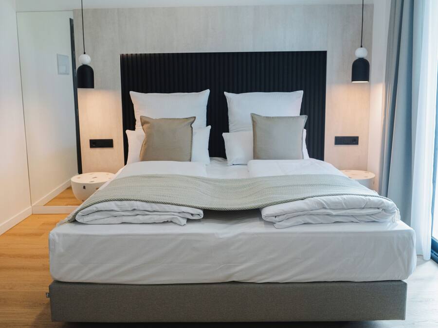 Una habitación de hotel moderna con una cama grande, una mesita de noche y una lámpara de pared.