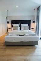 Una habitación de hotel moderna con una cama grande, una mesita de noche y una lámpara de pared.