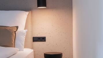 A modern bedroom with a bed, a bedside table, and a pendant light.