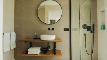 Een moderne badkamer met een ronde spiegel, een witte wastafel en een douche met glazen wanden.