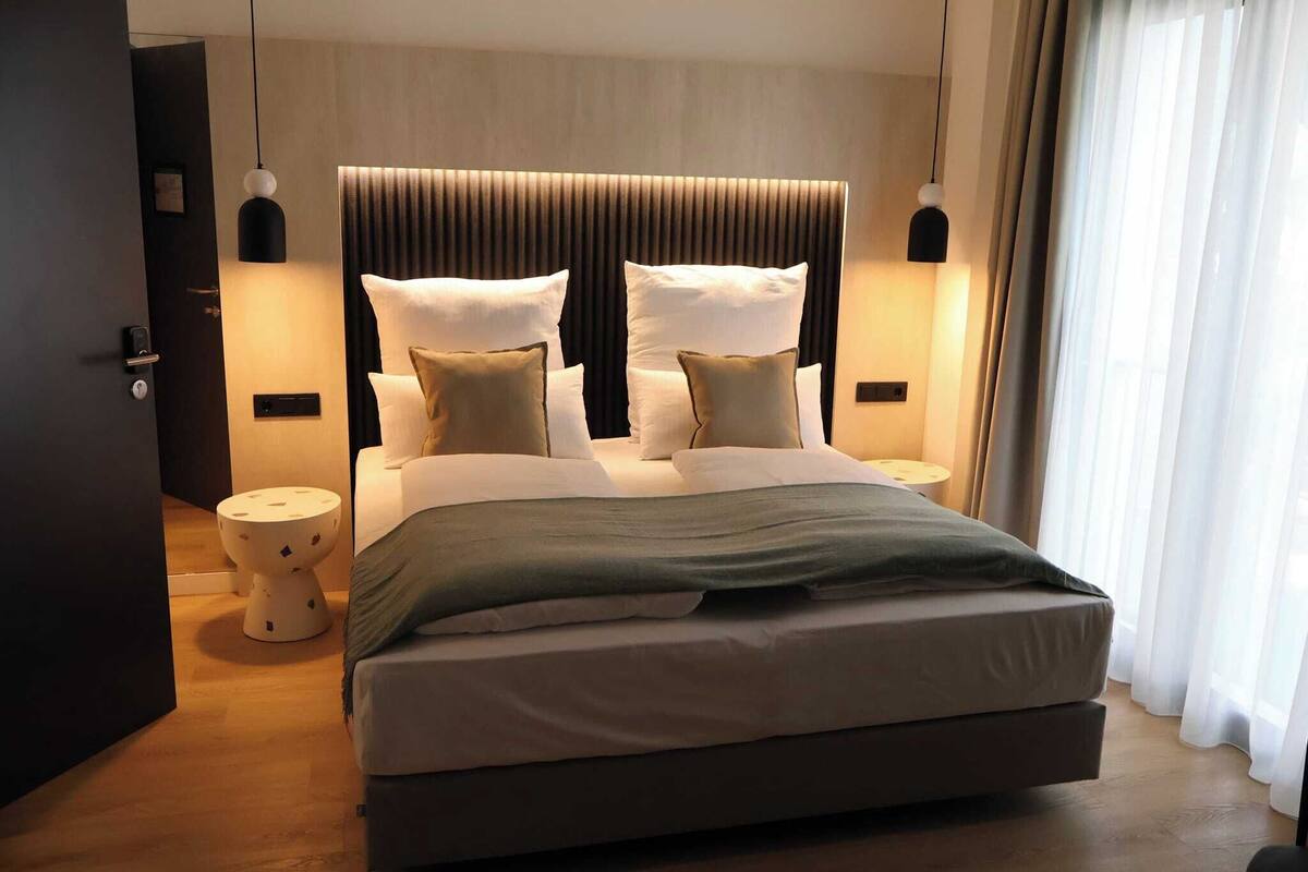 Een moderne slaapkamer met een groot bed, twee nachtkastjes en een hoofdbord met verticale lijnen.