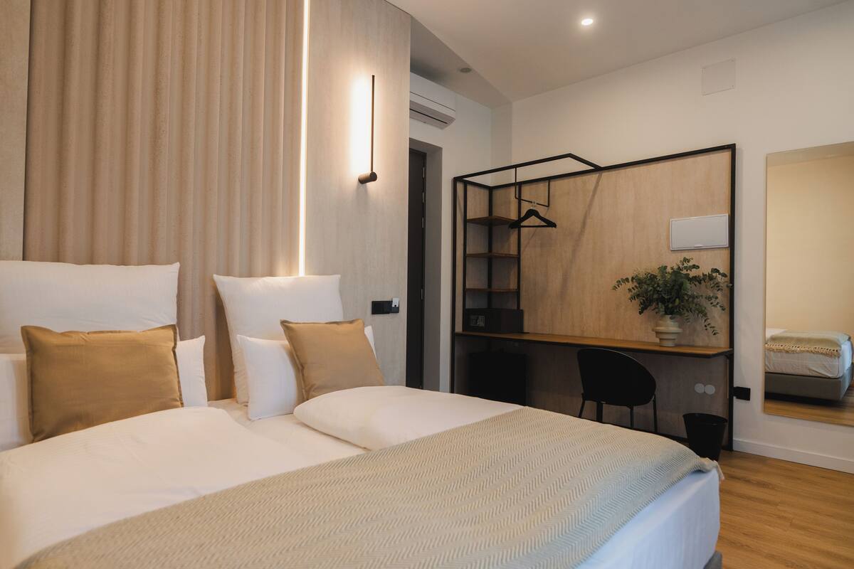 Een moderne hotelkamer met een groot bed, een bureau en een spiegel.