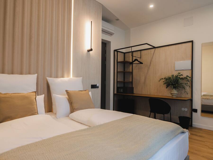 Una habitació d'hotel moderna amb un llit gran, una taula de treball i un mirall.