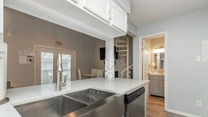 A modern kitchen with stainless steel appliances, a double sink, and a dishwasher. - Stay Salty @ Nautilus Galleria | Heated Pool (Corpus Christi)