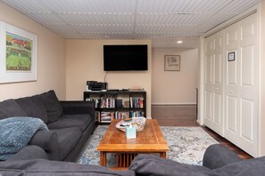 A living room with a sofa, a coffee table, a bookshelf, a flat-screen TV, and a door labeled 'Private.' - Spacious 3-Bedroom, 1.5-Bath Home in Central Maryland with Screened Porch & More (Severn)