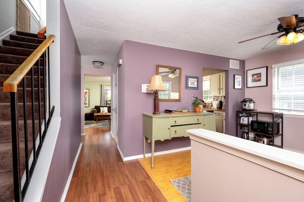 A hallway with a staircase, a dining area, and a kitchen with a microwave and toaster. - Spacious 3-Bedroom, 1.5-Bath Home in Central Maryland with Screened Porch & More (Severn)