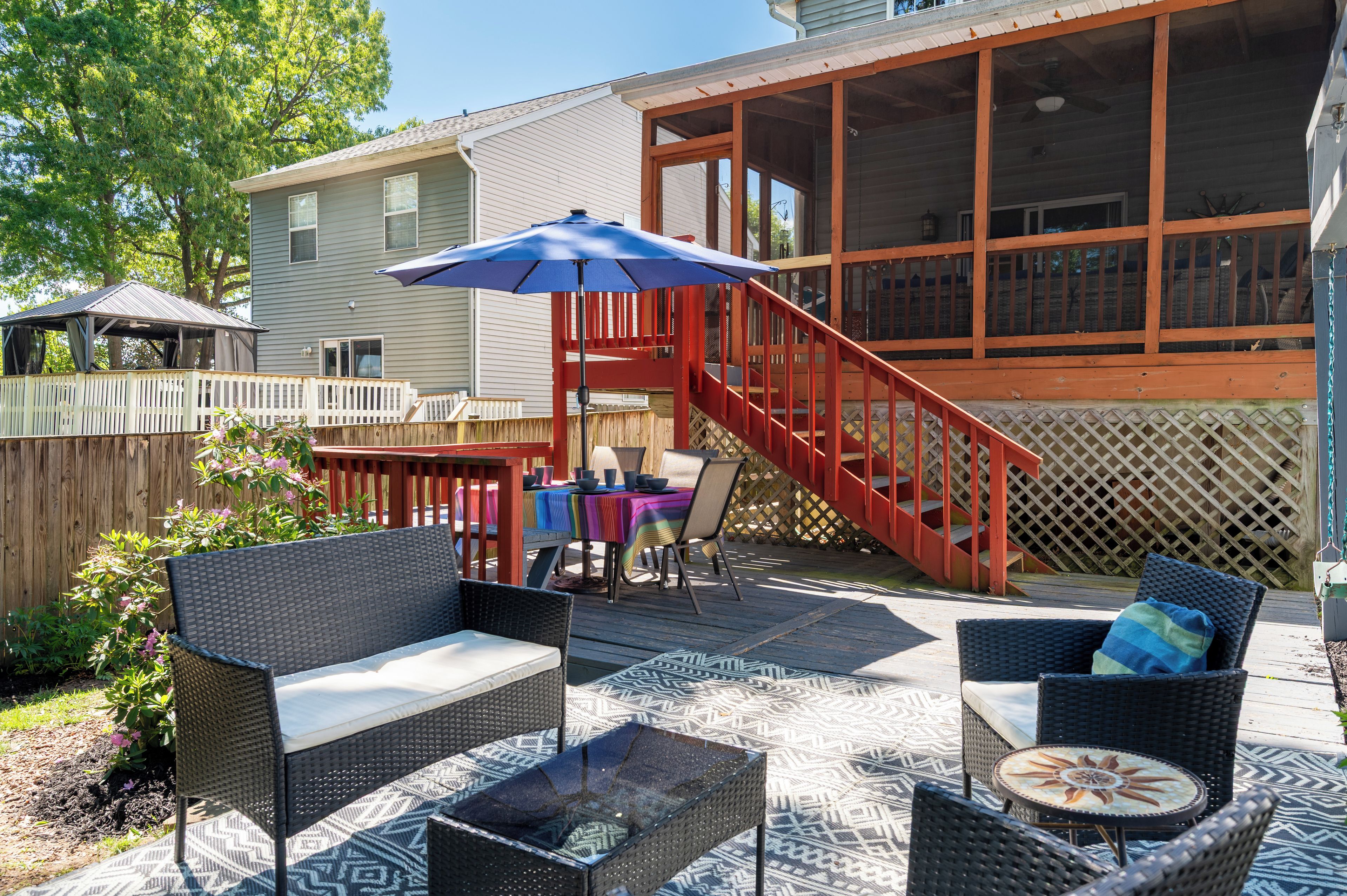 A patio with outdoor furniture, a covered seating area, and a staircase leading to a deck.