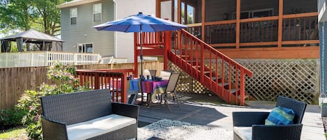 A patio with outdoor furniture, a covered seating area, and a staircase leading to a deck.