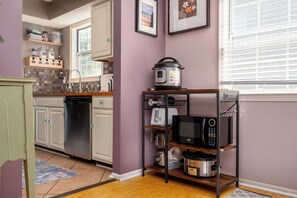 A compact kitchen with a dishwasher, a microwave, a slow cooker, and a coffee maker on a shelf. - Spacious 3-Bedroom, 1.5-Bath Home in Central Maryland with Screened Porch & More (Severn)