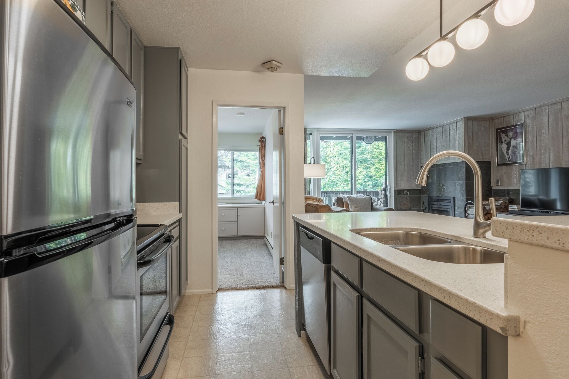 A modern kitchen with stainless steel appliances, a large island with a sink, and a view of the outdoors through a window.