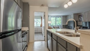 Una cocina moderna con electrodomésticos de acero inoxidable, una isla grande con pileta y vistas al exterior por una ventana.