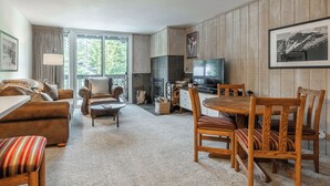 Una sala de estar acogedora con chimenea, televisor y comedor con mobiliario de madera.