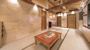Una habitación tradicional con tatami, una mesa de madera, suelo de tatami y vigas de madera en el techo.