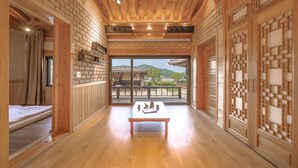 Una habitación de estilo japonés tradicional con paredes y suelos de madera, un tatami, una puerta corredera y vistas a un jardín tradicional.