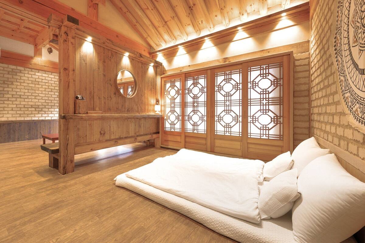 A wooden room with a bed, a bench, and a wall with a decorative screen.