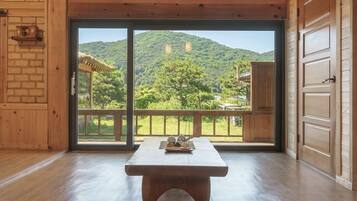 A wooden interior with a large sliding glass door leading to a balcony with a mountain view.