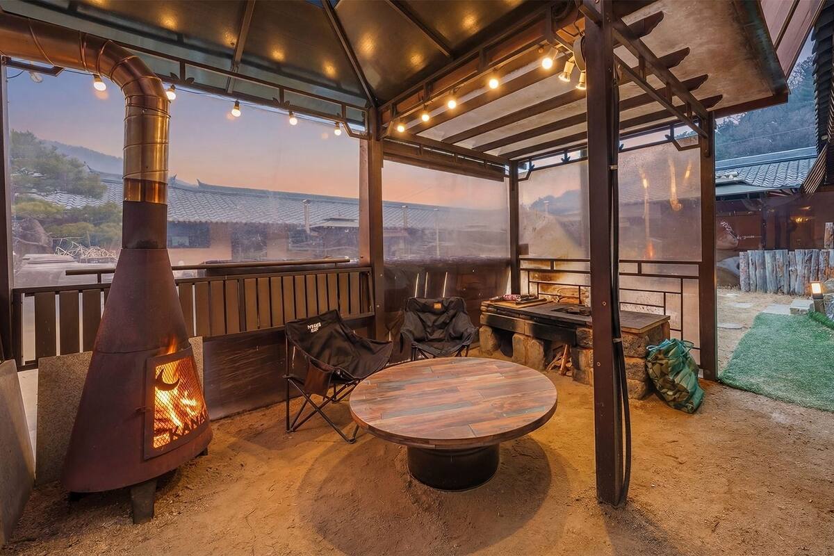 An outdoor seating area with a round table, a grill, and a view of the landscape.