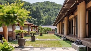 Ein traditionelles japanisches Gebäude mit überdachtem Gang, Blumentöpfen und einer Bergkulisse.