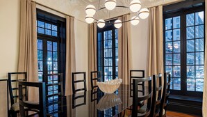Un coin repas avec une table en verre, des chaises noires et un vase décoratif servant de centre de table.