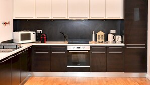 A modern kitchen with dark cabinets, a microwave, a toaster, and a small house-shaped container. - Bright & Perfectly Located! - Pass the Keys (Cardiff)