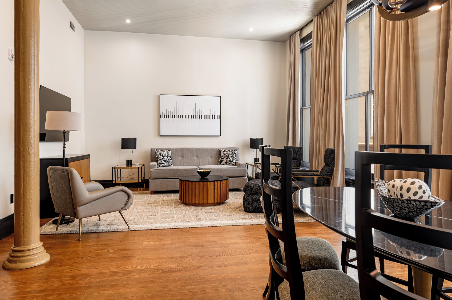A modern living room with a sofa, armchairs, a coffee table, and a dining area with a glass table and chairs.