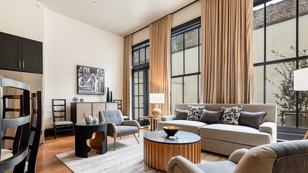 A modern living room with a sofa, armchairs, a coffee table, and a dining area with chairs and a table.