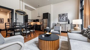 A modern living room with a dining area, kitchen, and a large window with curtains.