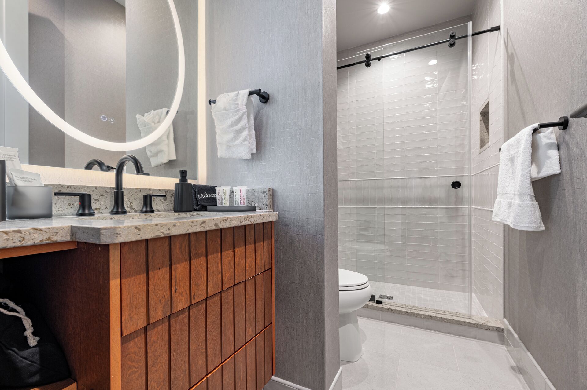A modern bathroom with a wooden vanity, a large mirror, and a shower area.