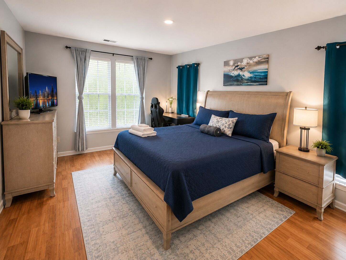 A bedroom with a bed, bedside tables, a desk, a chair, a TV, and a window with curtains.